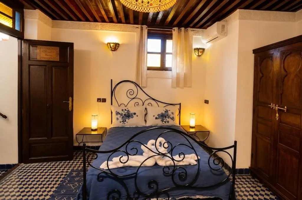 Chambre confortable du Riad Youssef à Fès avec lit en fer forgé et décoration authentique